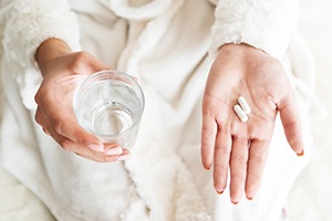 Person holding painkillers and a glass of water