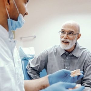 An older patient speaking with a dentist.