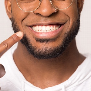 man pointing at his smile and enjoying the benefits of All-On-4 implants in Jupiter