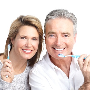 An older couple holding toothbrushes.