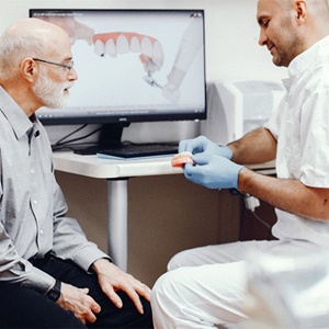 Dentist explaining dental implants to an older patient.
