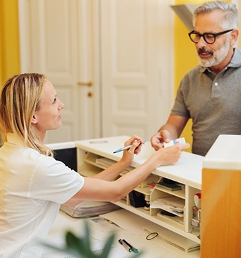 An older man speaking with a dental employee.