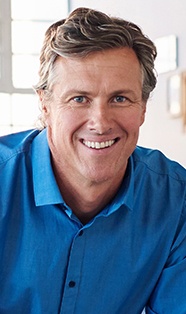 Older smiling man in dark blue collared shirt