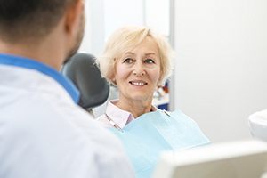 Man sitting on a log smiling with dental implants near Wellington