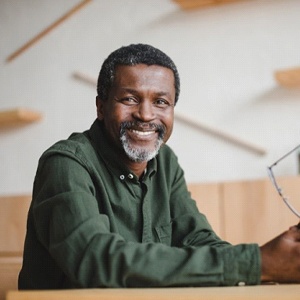 older man smiling and holding his glasses in his hands