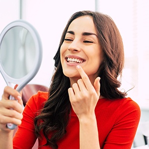 Woman with dental implants near Wellington checking smile in mirror