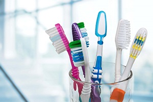 Six toothbrushes sitting in a clear glass 