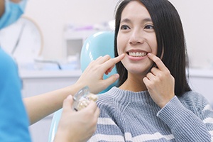 A young female pointing to the area of her missing tooth in preparation for dental implant surgery in Palm Beach Gardens