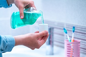 Person pouring mouthwash into its dedicated cap