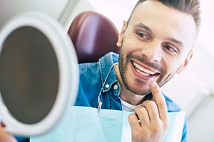 Patient using mirror while visiting an oral surgeon in Jupiter