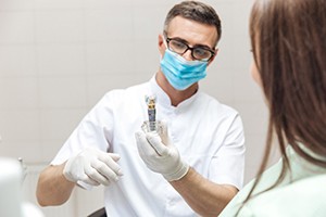 Jupiter implant dentist holding tooth model for patient