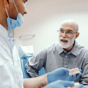 An older patient speaking with an oral surgeon.
