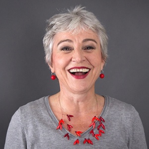 An older woman smiling after receiving dental implants.