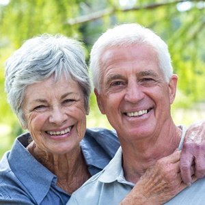 An older couple smiling and hugging outside.