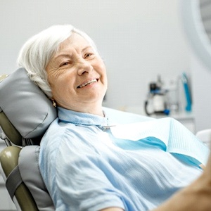 older woman admiring her smile in a handheld mirror