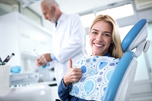 woman in dental chair giving thumbs up 