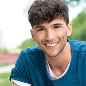 A young man smiling outside.