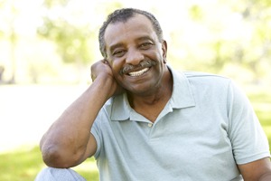 Man with mustache smiling while sitting outside on a sunny day