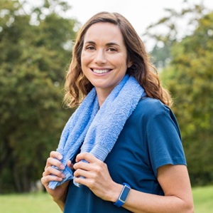 A woman outside with a towel around her neck.