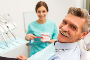 Elderly man with implant dentures smiling at dentist office 
