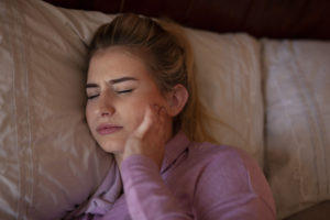 Young woman with wisdom tooth pain holding cheek