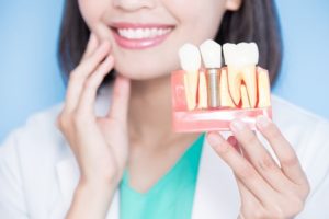 Person holding a model of dental implants.