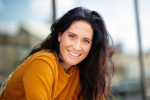 Woman in orange sweater sitting down and smiling