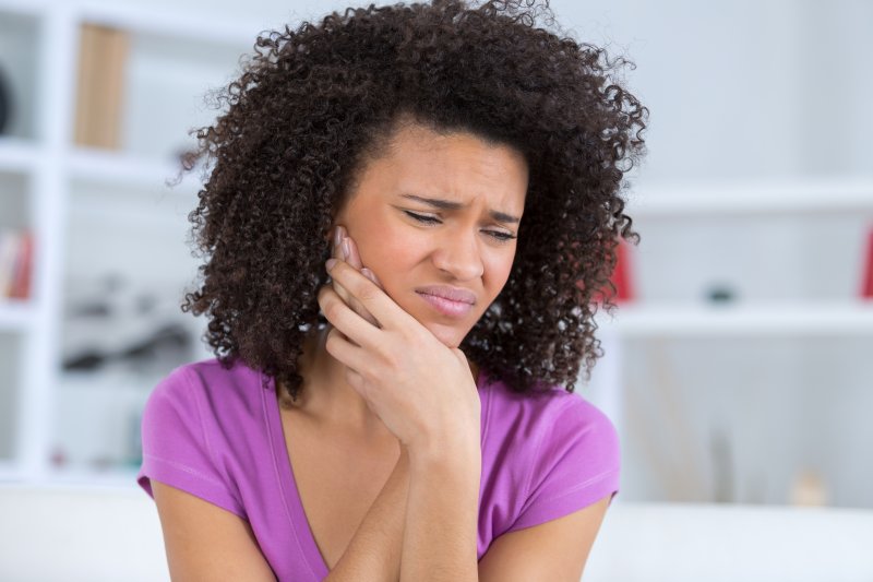 Woman holding her cheek due to impacted wisdom teeth