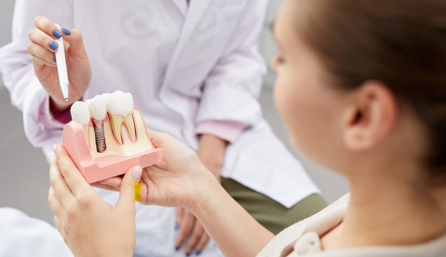 Patient holding dental implant model as dentist explains