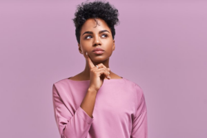 Woman tapping her finger to her cheek in a questioning pose